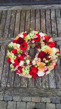 Rouwwerk 116: Bloemrijke (urne) krans in wit/rood/zalm/oranje & roze tinten