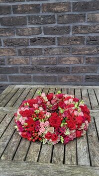 Rouwwerk 144: Bloemrijke (urne)krans rood & roze tinten