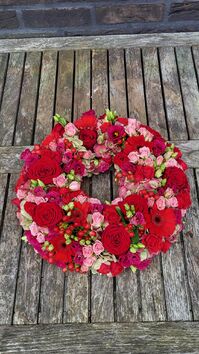 Rouwwerk 144: Bloemrijke (urne)krans rood & roze tinten