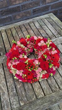 Rouwwerk 144: Bloemrijke (urne)krans rood & roze tinten