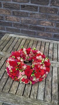 Rouwwerk 144: Bloemrijke (urne)krans rood & roze tinten