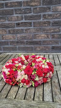 Rouwwerk 144: Bloemrijke (urne)krans rood & roze tinten